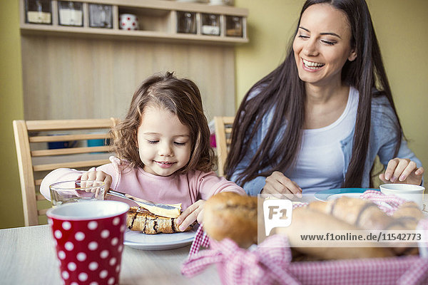 Porträt der Mutter und ihrer kleinen Tochter am Frühstückstisch