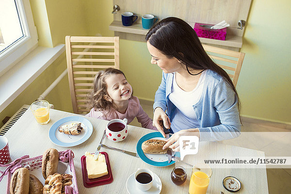 Mutter und ihre kleine Tochter am Frühstückstisch