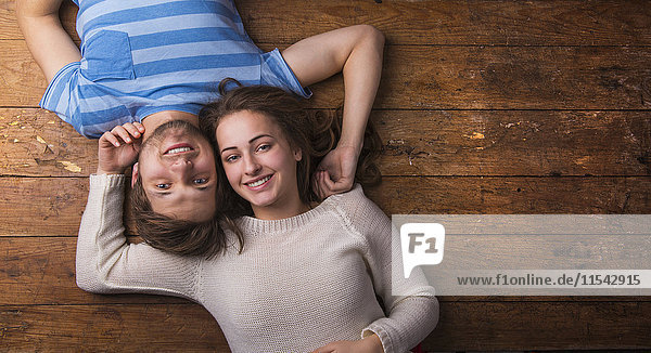 Glückliches junges verliebtes Paar auf Holzboden liegend