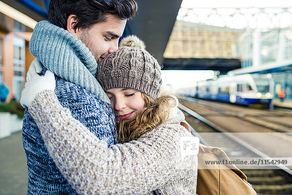 Smiling young couple embracing on station platform