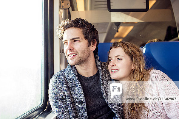 Smiling young couple in train car looking out of window