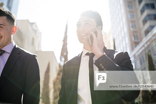 Businessman on cell phone in backlight with colleague