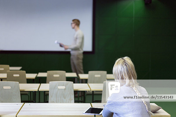 Junge Frau im Klassenzimmer mit Blick auf die Dozentin