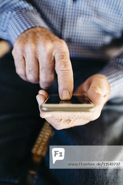 Hände des älteren Mannes mit Smartphone
