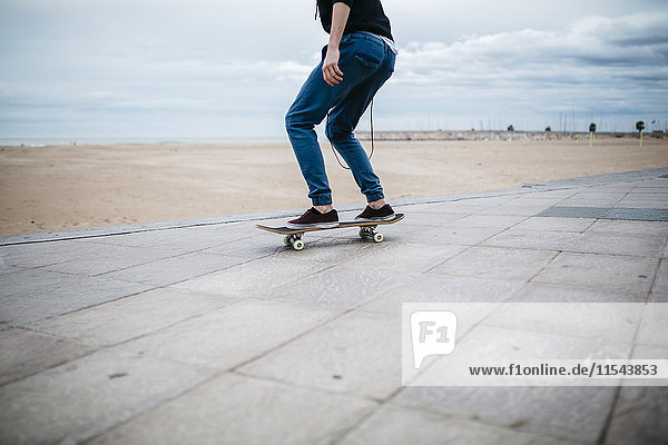 Spain  Torredembarra  young skateboarder in front of the beach  partial view