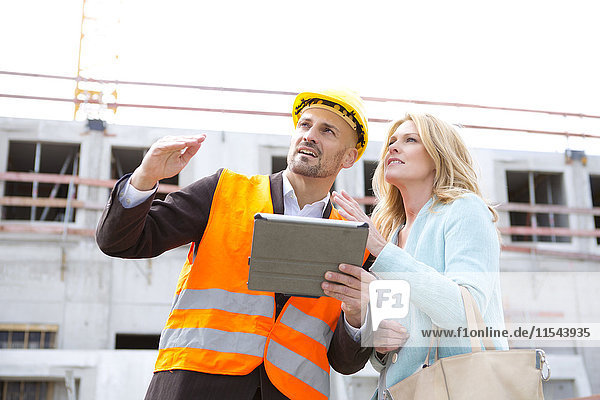Man with hard hat talking to woman on construction site