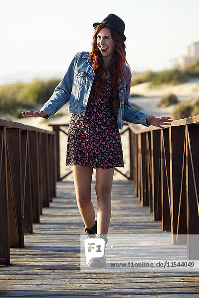 Spain  Cadiz  portrait of laughing young woman standing on boardwalk at the beach