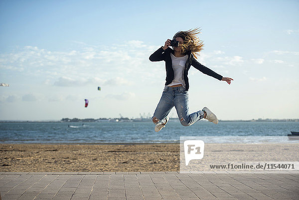 Spanien  Puerto Real  Frau fotografiert beim Springen in der Luft