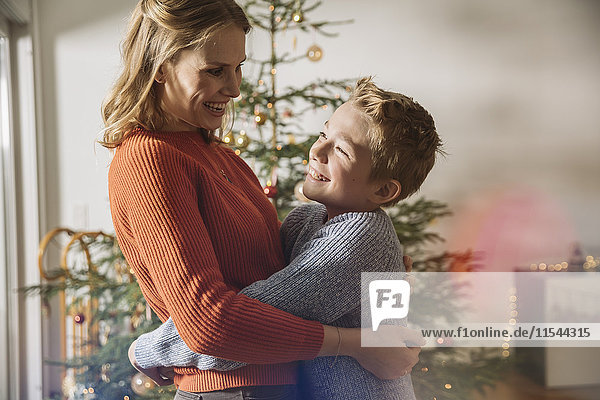 Glückliche Mutter und Sohn beim Umarmen am Weihnachtsbaum