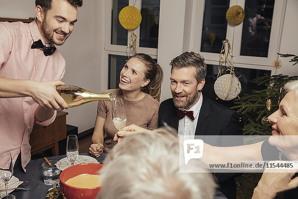 Fröhliche Gruppe von Freunden eröffnet am Silvesterabend Champagner