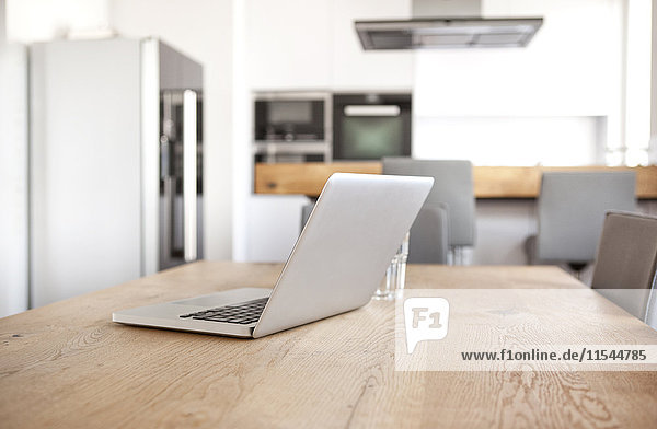 Laptop auf Holztisch in einer offenen Küche