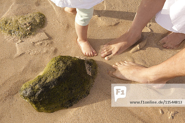 Füße der Familie im Sand am Strand stehend
