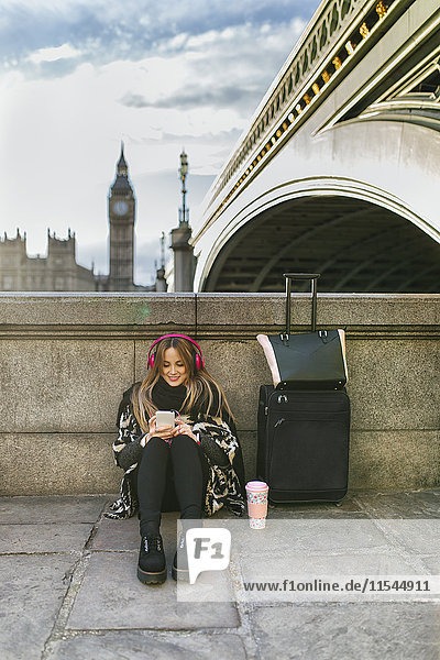 UK  London  junge Frau hört Musik in der Nähe der Westminster Bridge