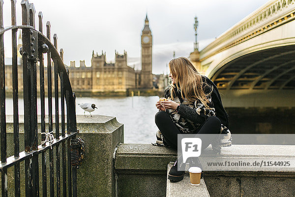 UK  London  junge Frau beim Snack in der Nähe der Westminster Bridge