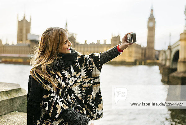 UK  London  junge Frau  die einen Selfie in der Nähe der Westminster Bridge nimmt.