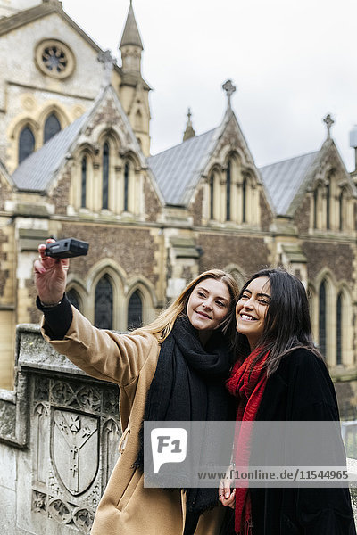 UK  London  Two friends exploring the city  photographing selves in front of Southwark Cathedral