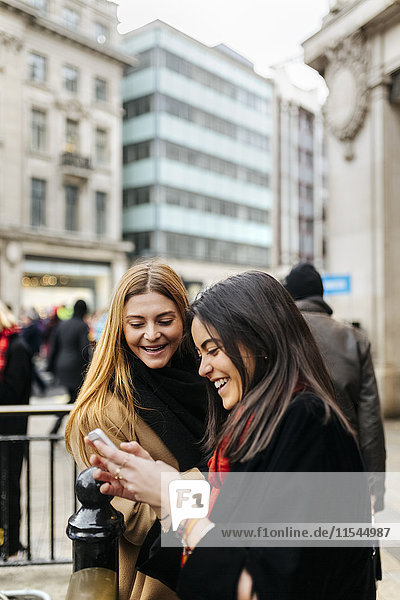 UK  London  Zwei Freunde erkunden die Stadt mit dem Smartphone
