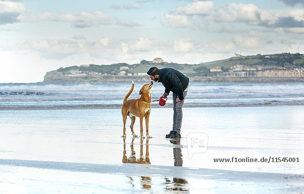 Spanien  Gijon  Mann mit seinem Hund am Strand