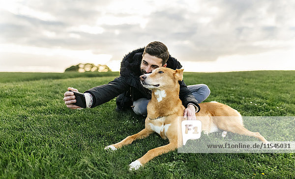 Man taking a selfie with his dog on a meadow