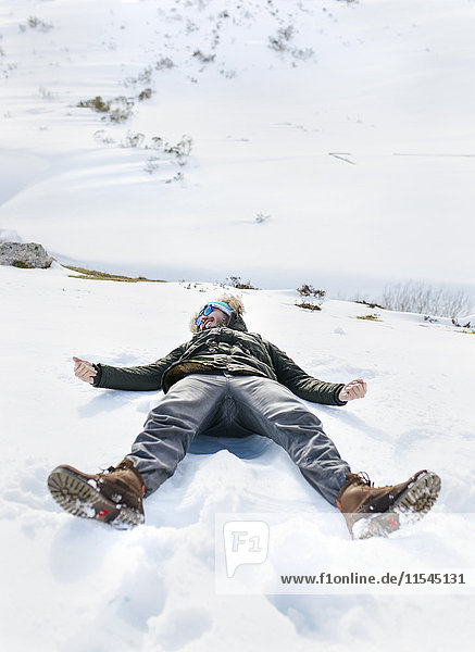 Spanien  Asturien  verspielter Mann im Schnee liegend