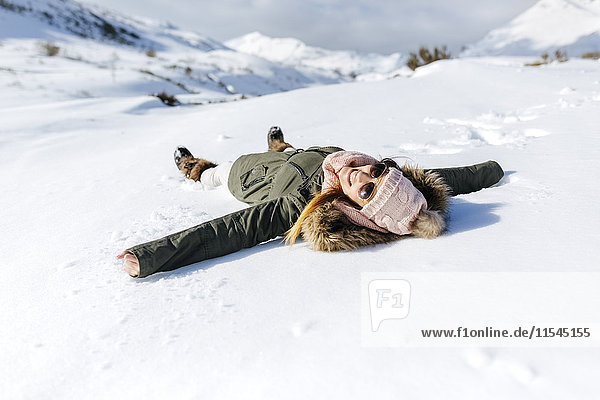 Spain  Asturias  playful woman lying in snow