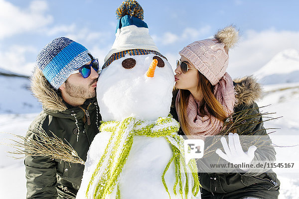Spanien  Asturien  Paar küsst einen Schneemann