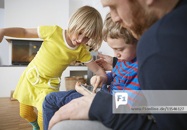 Vater und zwei Kinder mit digitalem Tablett