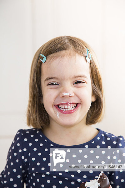 Portrait of laughing little girl eating chocolate marshmallow