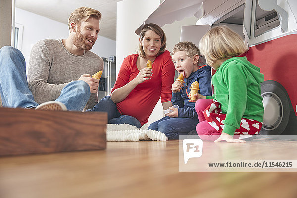 Glückliche Familie mit Eis am Stiel und Modellauto im Wohnzimmer