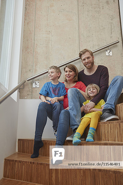 Porträt einer lächelnden Familie auf einer Treppe sitzend