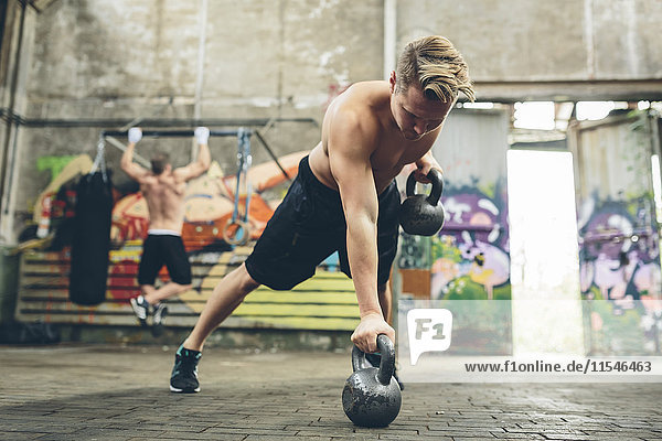 Young man having a workout with kettlebells