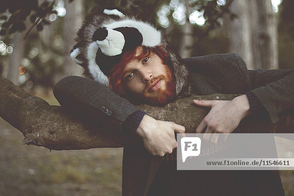Portrait of redheaded young man wearing raccoon hat in the woods