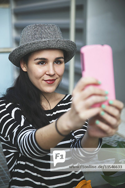 Porträt einer jungen Frau  die einen Selfie mit einem Smartphone nimmt.