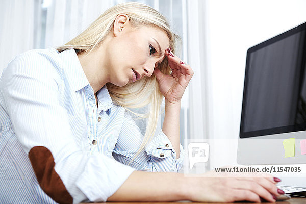 Overstressed blond woman sitting at her desk