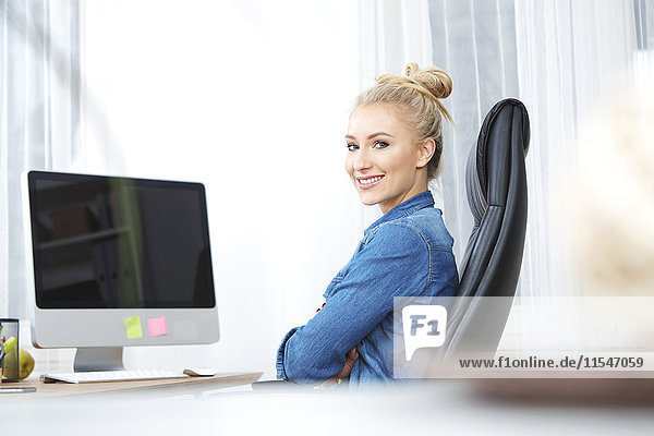 Portrait od smiling blond woman sitting at desk in her office