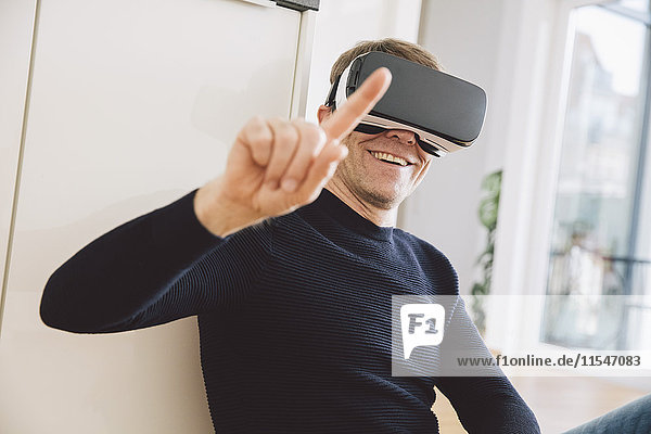 Smiling man wearing virtual reality glasses pointing his finger