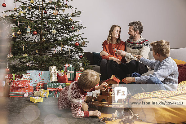 Eine vierköpfige Familie  die Weihnachtsgeschenke auspackt und mit Noah's Ark spielt.
