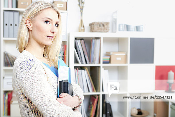 Porträt einer blonden Frau mit Dokumenten im Home-Office