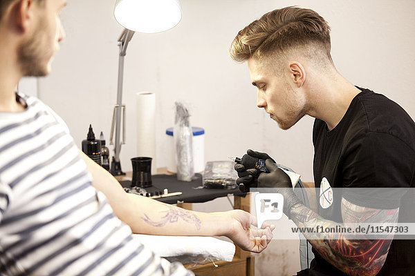 Tätowierer bei der Arbeit in seinem Tattoostudio