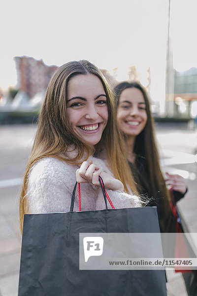 Portrait einer glücklichen jungen Frau mit Einkaufstaschen