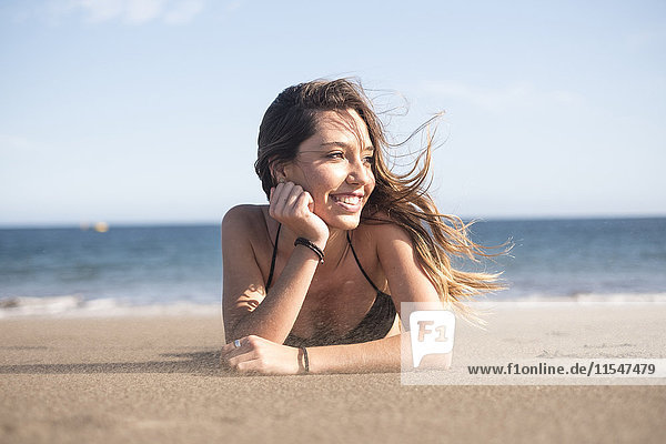 Spanien  Teneriffa  Porträt einer jungen Frau  die sich am Strand entspannt