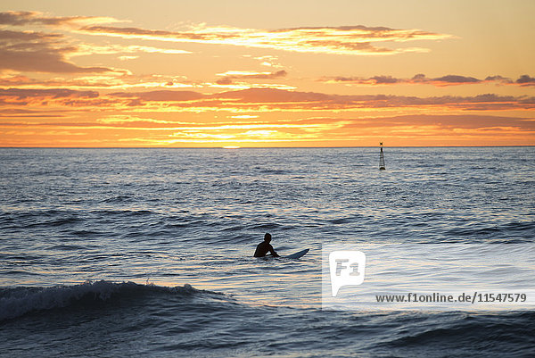 Surfer in the sea at sunrise