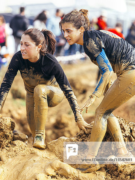 Participants in extreme obstacle race  running through mud