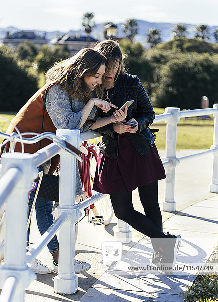 Zwei junge Frauen im Freien beim Blick auf das Handy