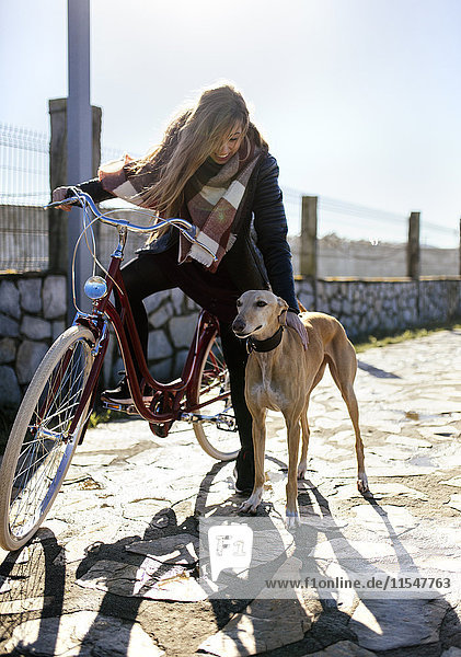 Junge Frau mit Fahrrad und Windhund