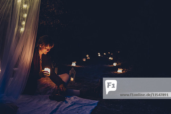 Frau in einem romantischen Lager bei Kerzenlicht in der Natur