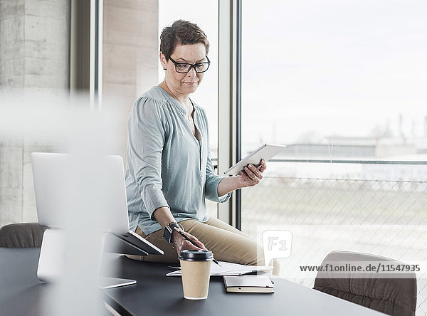 Geschäftsfrau mit digitalem Tablett und Notizblock im Büro