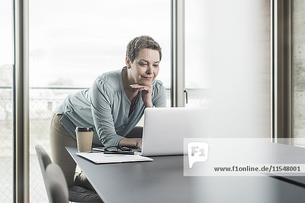 Businesswoman looking at laptop in office