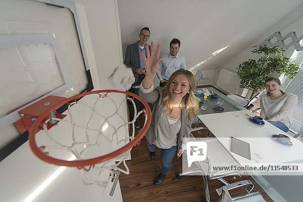 Glückliche Frau spielt Basketball im Konferenzraum