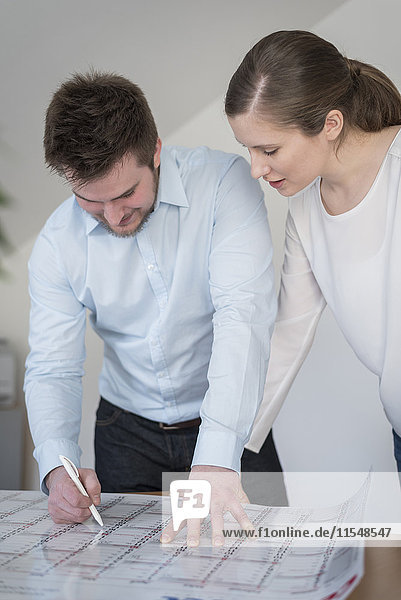 Young man and woman in office looking at calendar